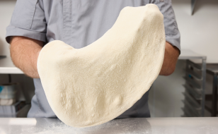 A person holding pizza dough